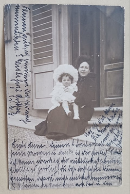 Äiti ja tytär poseeraavat talon edessä, valokuvapk, p. 1905