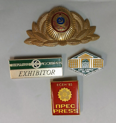 Hattumerkki ja kolme pinssiä