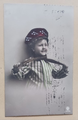 Iloinen lapsi pukemassa kaulaliinaa, väripk, p. 1911