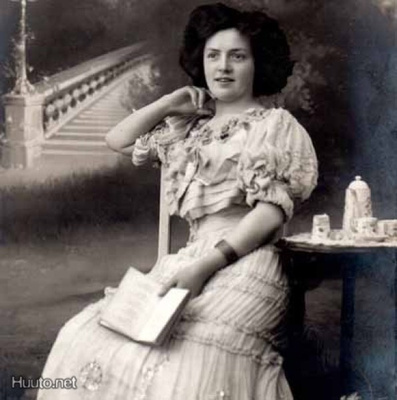 NAINEN / Tyttö lukee katetun pöydän luona. 1900-l.