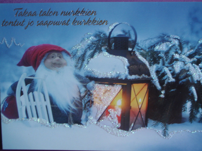 Tonttu pihalla kelkan ja lyhdyn kanssa
