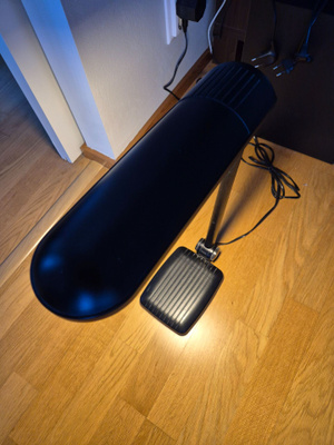Musta pöytälamppu nivelvarrella