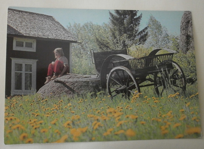 Tyttö mökin pihalla, vanhat hevosrattaat, ei p.