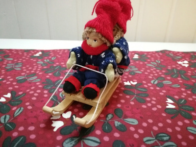 Tonttutyttö ja -poika kelkkailemassa figuuri