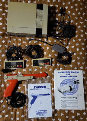 NES konsoli + 7 peliä + Zapper + Game Genie + koodivihko