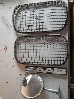 Saab 96. Lamppujen kivi iskusuojat, peili ja nimikyltti.