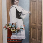 Leidi kansanpuvussa kukkien kanssa ovella, p. 1908 - pikkukuva 1