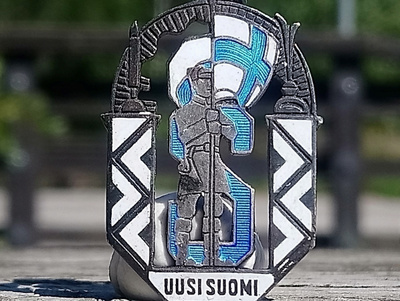 Hopeinen emalinen Uusi Suomi merkki. Halkaisija - 31 mm.