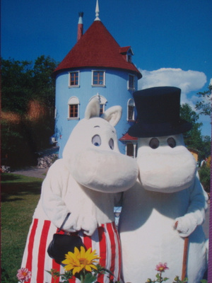 Muumimamma ja -pappa poseeraavat kukkapenkin edessä