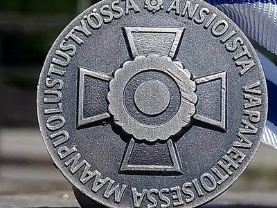 Hopeavärinen Maanpuolustustyöstä. Valmistajan leimalla. Halk