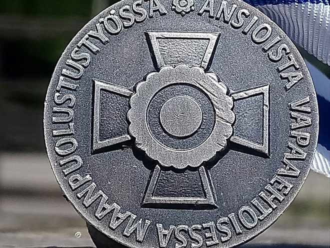 Hopeavärinen Maanpuolustustyöstä. Valmistajan leimalla. Halk
