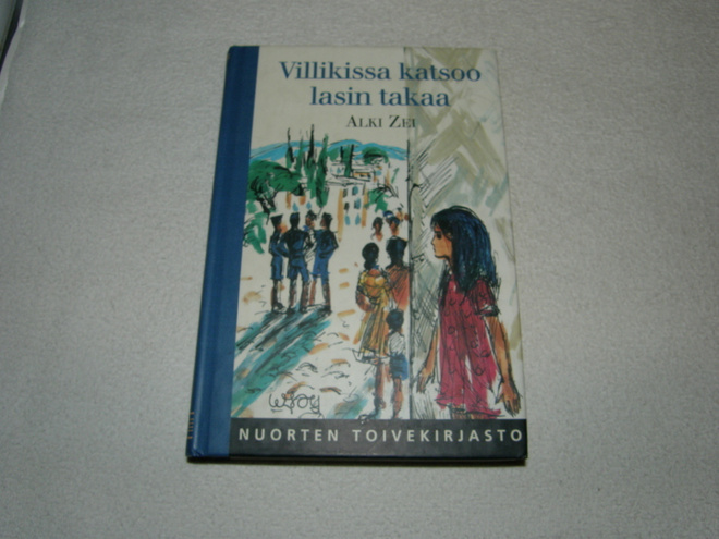 Alki Zei Villikissa katsoo lasin takaa